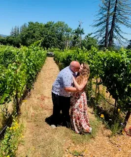 A couple sharing a kiss in a sunlit vineyard row