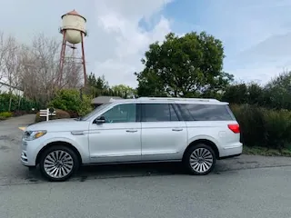 A silver Lincoln Navigator parked in front of a vintage water tower